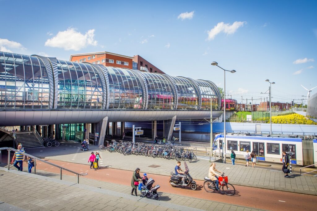 Foto van een tramhalte, voetgangersviaduct en mensen in de stad