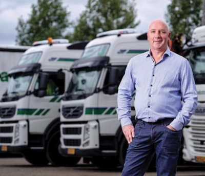 Portretfoto van Wilbert van Uden met op de achtergrond een aantal vrachtwagens die geparkeerd staan